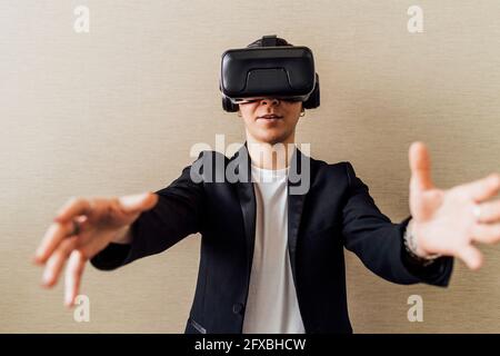 Femme d'affaires qui fait des gestes tout en utilisant un micro-casque de réalité virtuelle au bureau Banque D'Images