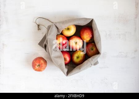 Pommes collectées dans un sac sur fond blanc texturé Banque D'Images