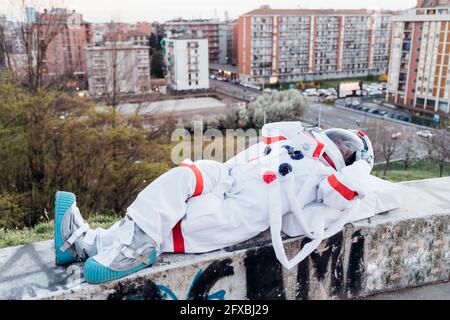 Femme astronaute en costume spatial se détendant sur le mur de soutènement Banque D'Images