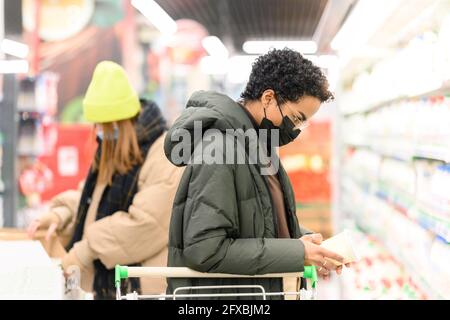 Des amies féminines portant un masque facial de protection lors de l'achat d'articles d'épicerie au supermarché pendant le COVID-19 Banque D'Images