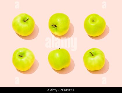Prise de vue en studio de six pommes vertes sur fond rose clair Banque D'Images