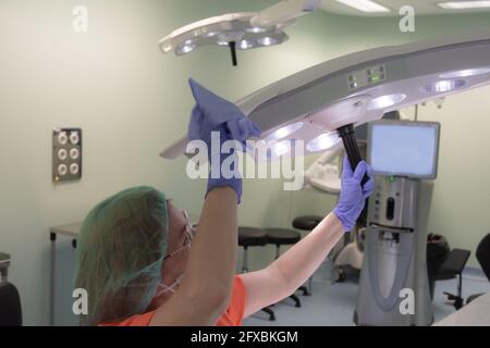 Nettoyage de la femme avec des gants, un capuchon, un masque et une désinfection uniforme de la lampe dans la salle d'opération Banque D'Images