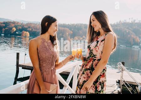 Belles femmes avec verres sur la jetée au-dessus du lac Banque D'Images