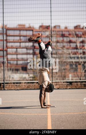 Homme avec des jambes à part faire une activité acrobatique sur le terrain de basket-ball Banque D'Images