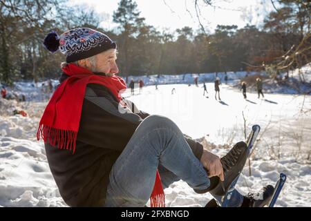 Homme âgé portant un patin à glace pendant l'hiver Banque D'Images
