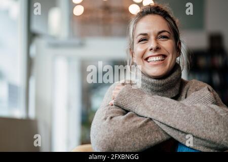 Femme adulte de taille moyenne portant un chandail souriant au café Banque D'Images