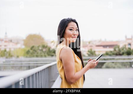 Belle femme tenant un smartphone sur une passerelle surélevée Banque D'Images