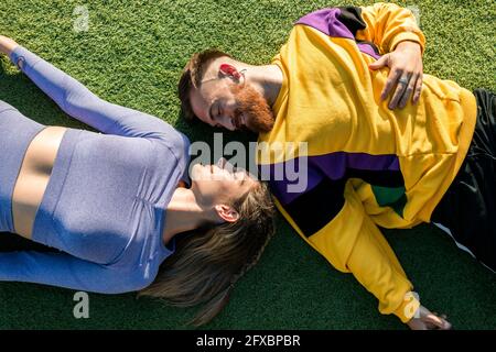 Homme souriant couché par une femme sur l'herbe pendant la journée ensoleillée Banque D'Images