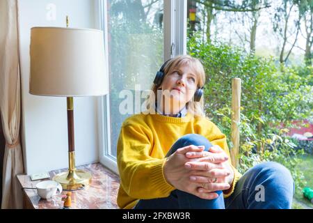 Une femme attentionnés qui écoute de la musique dans un casque à la maison Banque D'Images