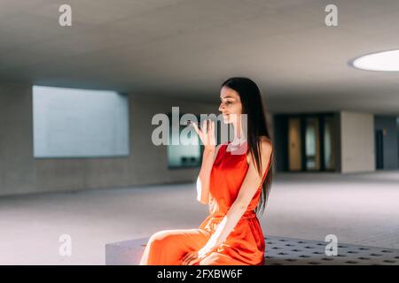 Femme d'affaires vêtue de rouge, envoyant un message vocal avec son téléphone mobile à l'intérieur. Banque D'Images