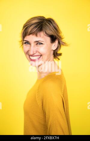 Femme mûre et gaie debout sur fond jaune Banque D'Images
