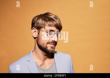 Homme barbu et attentionné qui regarde devant le mur jaune Banque D'Images