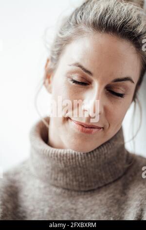 Belle femme avec les yeux fermés devant un fond blanc Banque D'Images