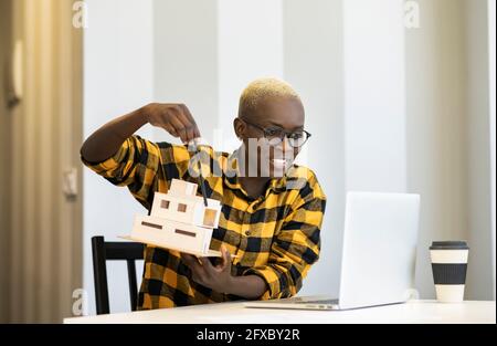 Femme architecte souriante expliquant le modèle lors d'une visioconférence à partir d'un ordinateur portable à la maison Banque D'Images