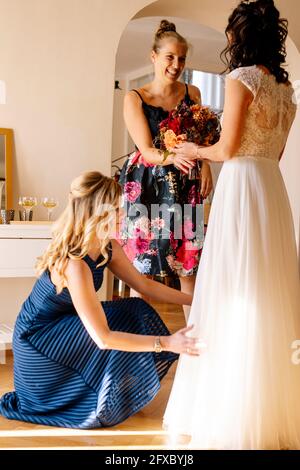 Femme souriante donnant un bouquet à la mariée dans la chambre familiale Banque D'Images