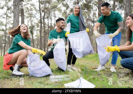 De jeunes amis écologistes ramassant des déchets dans un sac en plastique en forêt Banque D'Images