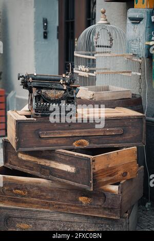 Vieille machine à écrire debout sur des boîtes en bois à côté de la cage pour les oiseaux. Articles vintage élégants et élégants Banque D'Images