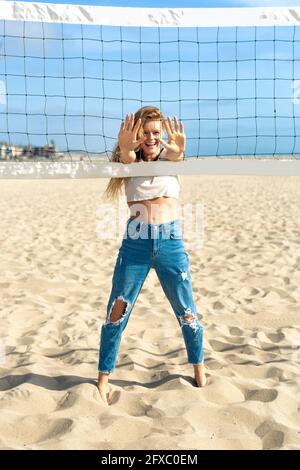 Femme montrant les mains tout en jouant au volley-ball sur le sable pendant la journée ensoleillée Banque D'Images