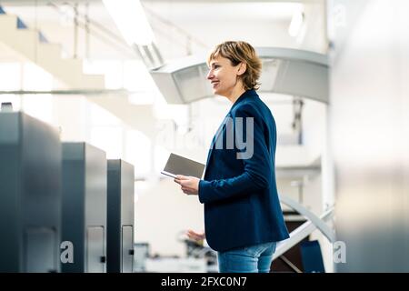 Femme souriante avec tablette numérique à l'usine d'impression Banque D'Images