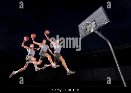 Image multiple d'un jeune homme qui saute pendant qu'il joue au basket-ball la nuit Banque D'Images