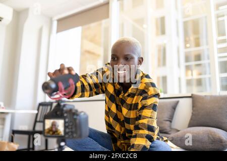 Femme souriante qui règle le microphone pendant qu'elle se vante à la maison Banque D'Images