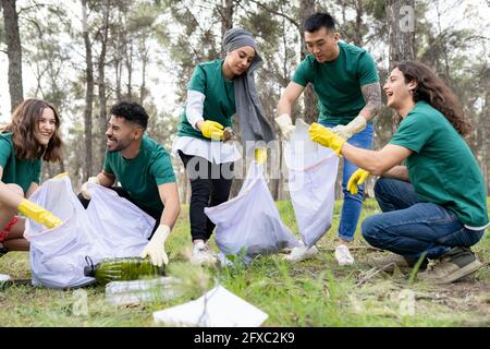 Souriants, hommes et femmes bénévoles collectant du plastique dans la forêt Banque D'Images