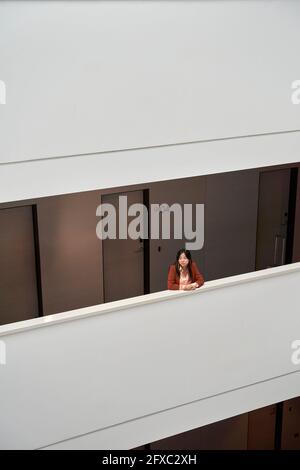 Femme d'affaires attentionnés qui regarde loin tout en s'appuyant sur le mur de soutènement de l'hôtel Banque D'Images