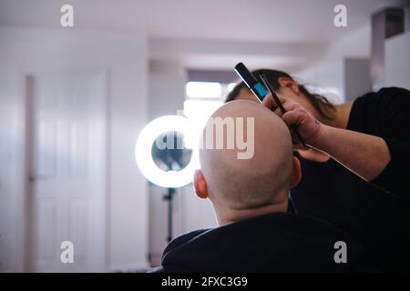 Femme maquilleur faisant le maquillage d'un mannequin chauve en studio Banque D'Images