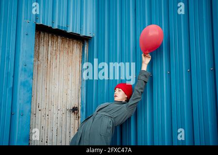 Femme tenant le ballon tout en se repliant vers l'arrière sur l'obturateur bleu Banque D'Images