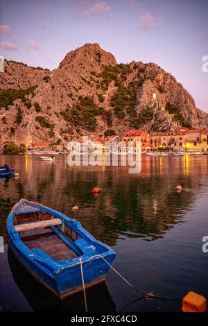 Croatie, comté de Split-Dalmatia, omis, barque amarré en face de la ville côtière au crépuscule Banque D'Images