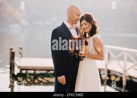 Couple portant une robe de mariage embrassant au bord du lac Banque D'Images