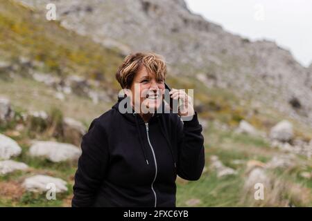 Femme âgée souriante parlant sur téléphone portable dans la nature Banque D'Images