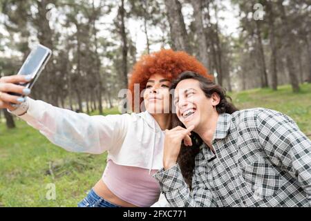 Homme prenant le selfie avec une jeune femme pendant la fête dans la forêt Banque D'Images