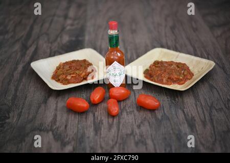 2 bols identiques avec une salsa fraîchement préparée et une bouteille de sauce tabasco Banque D'Images