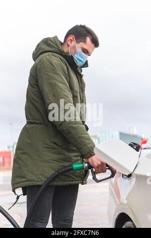 Homme avec masque facial de protection ravitailleur de voiture à la station-service pendant COVID-19 Banque D'Images