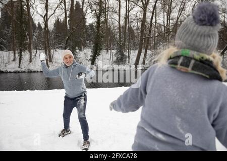 Homme qui jette un ballon de neige sur une femme pendant l'hiver Banque D'Images