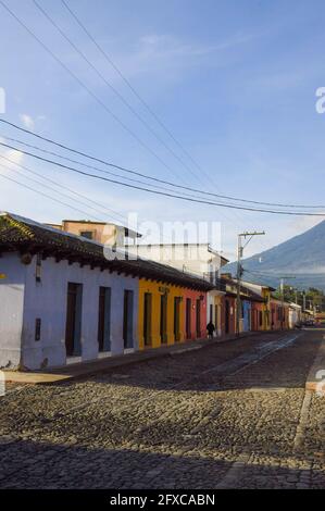 ANTIGUA, GUATEMALA - 01 août 2019 : maisons basses et colorées sur une rue pavée au lever du soleil avec un ciel bleu à Antigua, Guatemala. Banque D'Images