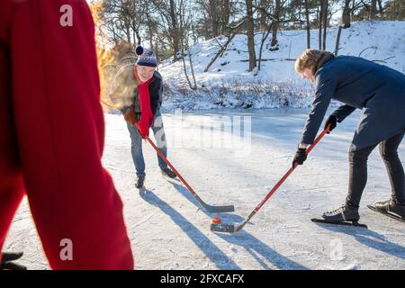 Homme senior jouant au hockey sur glace avec des amis sur la neige en hiver Banque D'Images