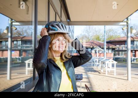 Femme souriante portant un casque de sport pendant la journée ensoleillée Banque D'Images