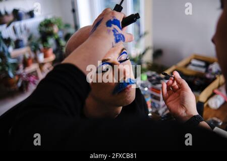 Maquilleuse féminine appliquant du maquillage sur un modèle masculin en studio Banque D'Images