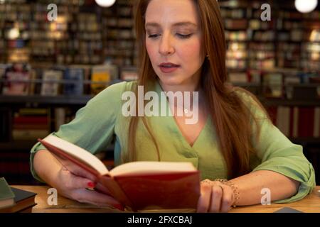 Belle femme lisant le livre dans la bibliothèque Banque D'Images