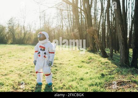 Femme explorer portant une combinaison d'espace debout dans la forêt le jour ensoleillé Banque D'Images