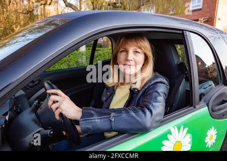 Femme d'âge mûr assise sur le siège conducteur dans la voiture Banque D'Images