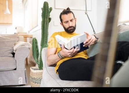 Homme dans des vêtements décontractés livre de lecture à la maison Banque D'Images