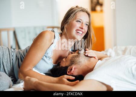 Cheerful young couple lying on bed at home Banque D'Images