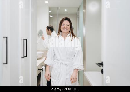 Femme souriante portant un peignoir dans la salle de bains de l'hôtel Banque D'Images