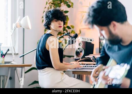 Musicienne regardant le guitariste masculin en studio Banque D'Images