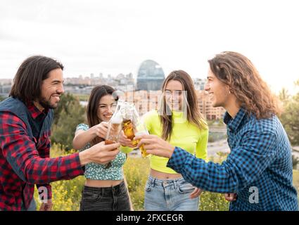 Les hommes aux cheveux longs avec les femmes toaster les bouteilles de bière Banque D'Images