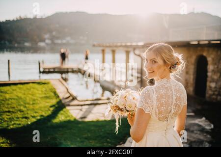 Belle mariée avec bouquet de vue sur l'épaule le jour ensoleillé Banque D'Images