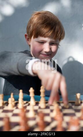 Un garçon intelligent jouant aux échecs devant le mur Banque D'Images